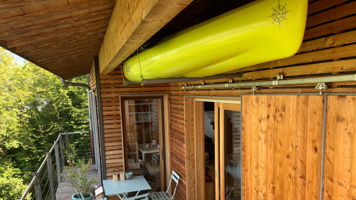 Le kayak vient se suspendre au plafond, directement sous l'avant-toit, dégageant la terrasse située juste en dessous.